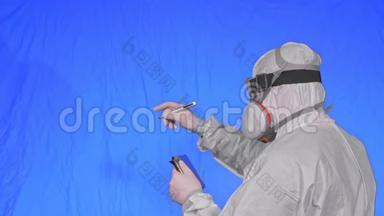 科学家病毒学家在呼吸器上用手写笔在平板电脑上写字。戴防护口罩的男子